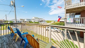 A wooden deck with chairs, a view of the beach, and a flag. - Too Close - KDH MP 6, Ocean Views, 65 Yards to Beach, Foosball, 2 Kitchens, Flex Stays (Kill Devil Hills)