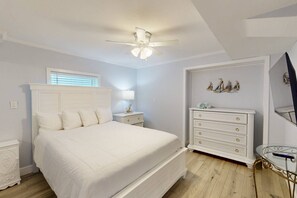 Un dormitorio con cama, mesita de noche, cómoda y ventilador de techo.