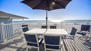 Una terraza con mesa y sillas, con vista a la playa.