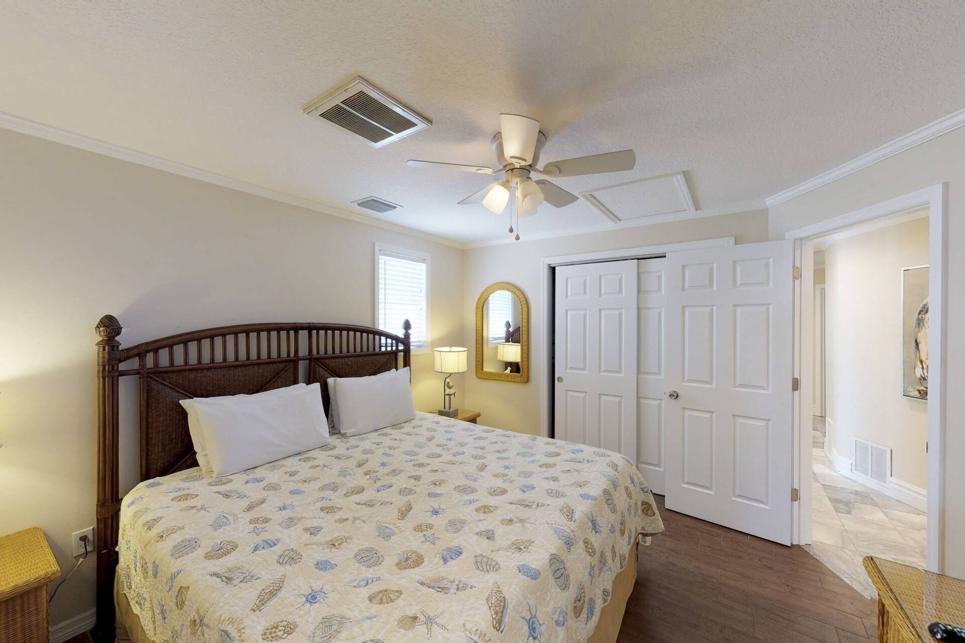 A bedroom with a bed, a ceiling fan, a door, and a window.