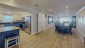Una cocina amplia con una isla central, un comedor con una mesa grande y sillas, y vista al salón.