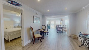 Una habitación amplia con cama, un comedor con mesa y sillas, y un pasillo que conduce a otra habitación.
