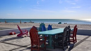 Un patio frente a la playa con una mesa y sillas, con vista al océano.