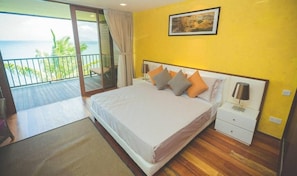 Relax in this serene retreat with a large bed, a nightstand, and a sliding glass door leading to a balcony with ocean views.