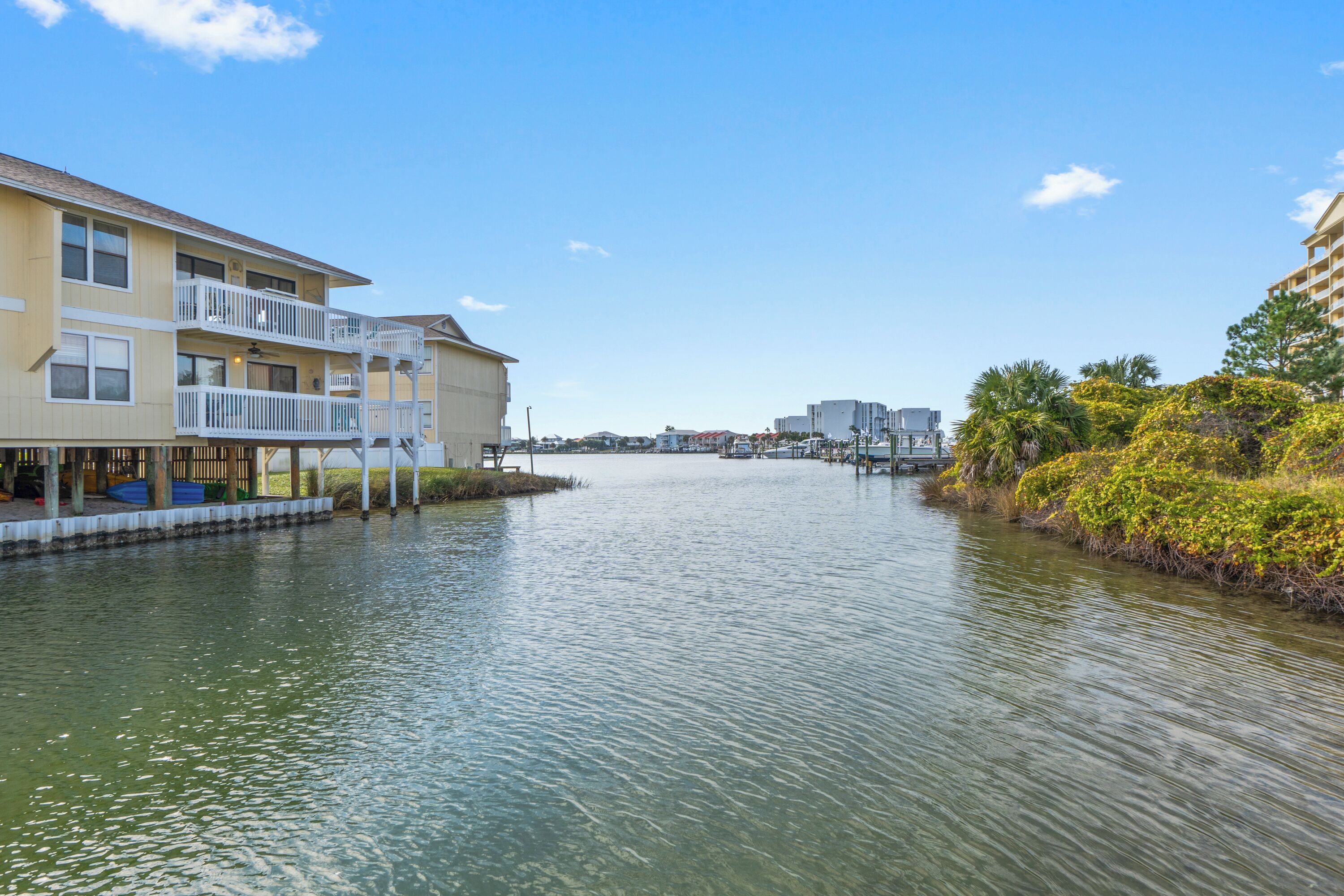 A waterfront hotel with balconies, a river, and surrounding greenery.