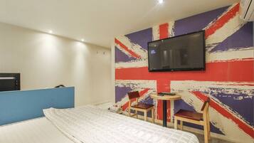 A hotel room with a bed, a television mounted on the wall, and a small table with two chairs.