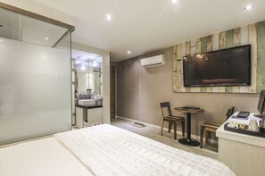 A modern hotel room with a large bed, a desk with a computer, a TV, and a small seating area. - Cube Hotel (Busan)