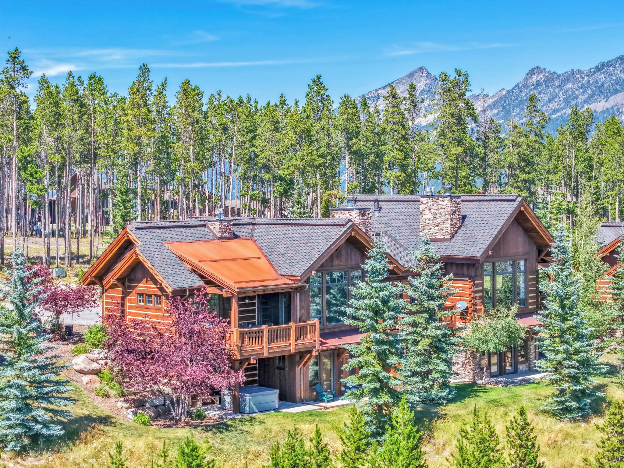 A lodge with multiple cabins, surrounded by a forest and mountains.