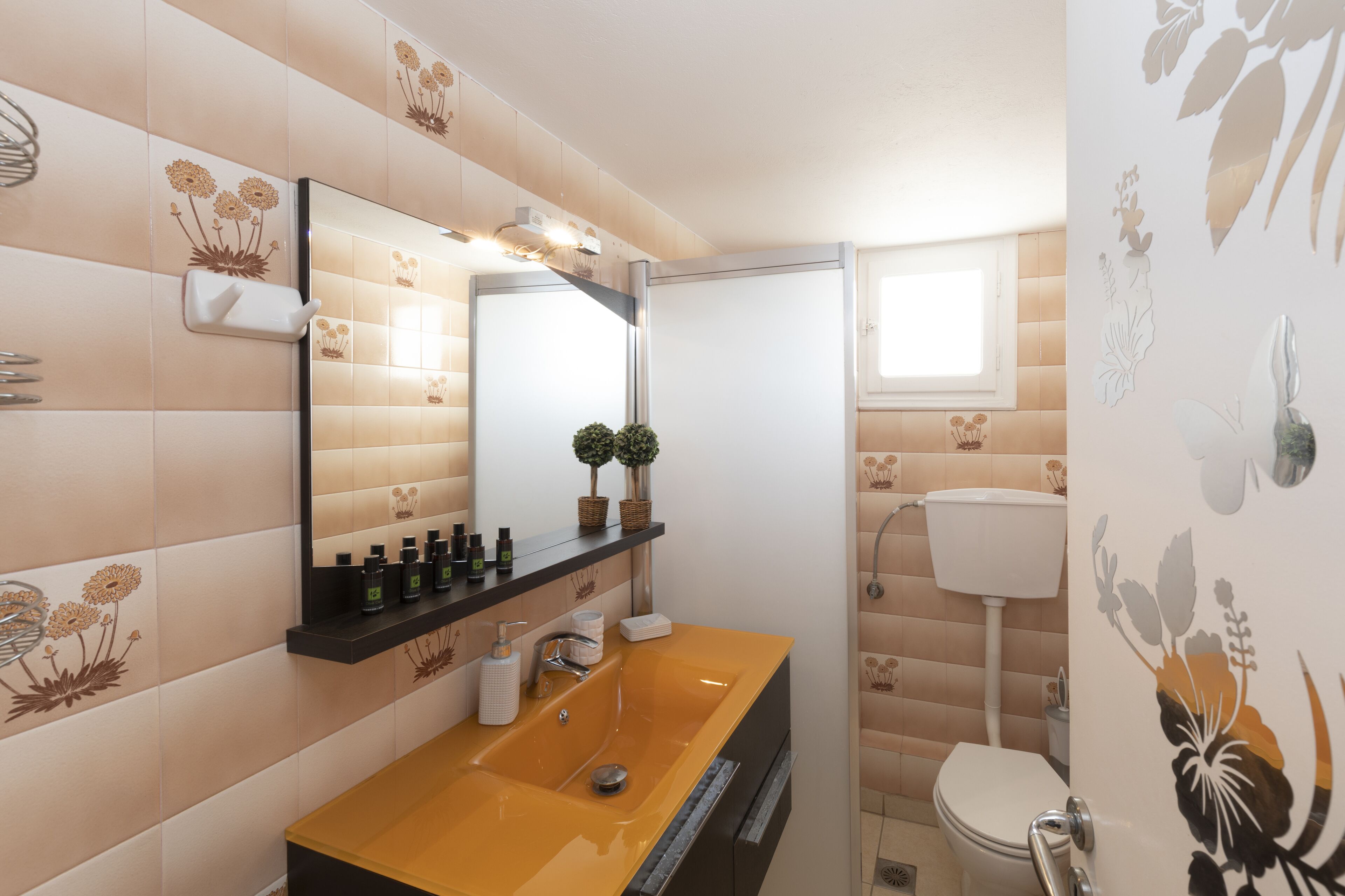 A bathroom with a yellow sink, a mirror, and a toilet.