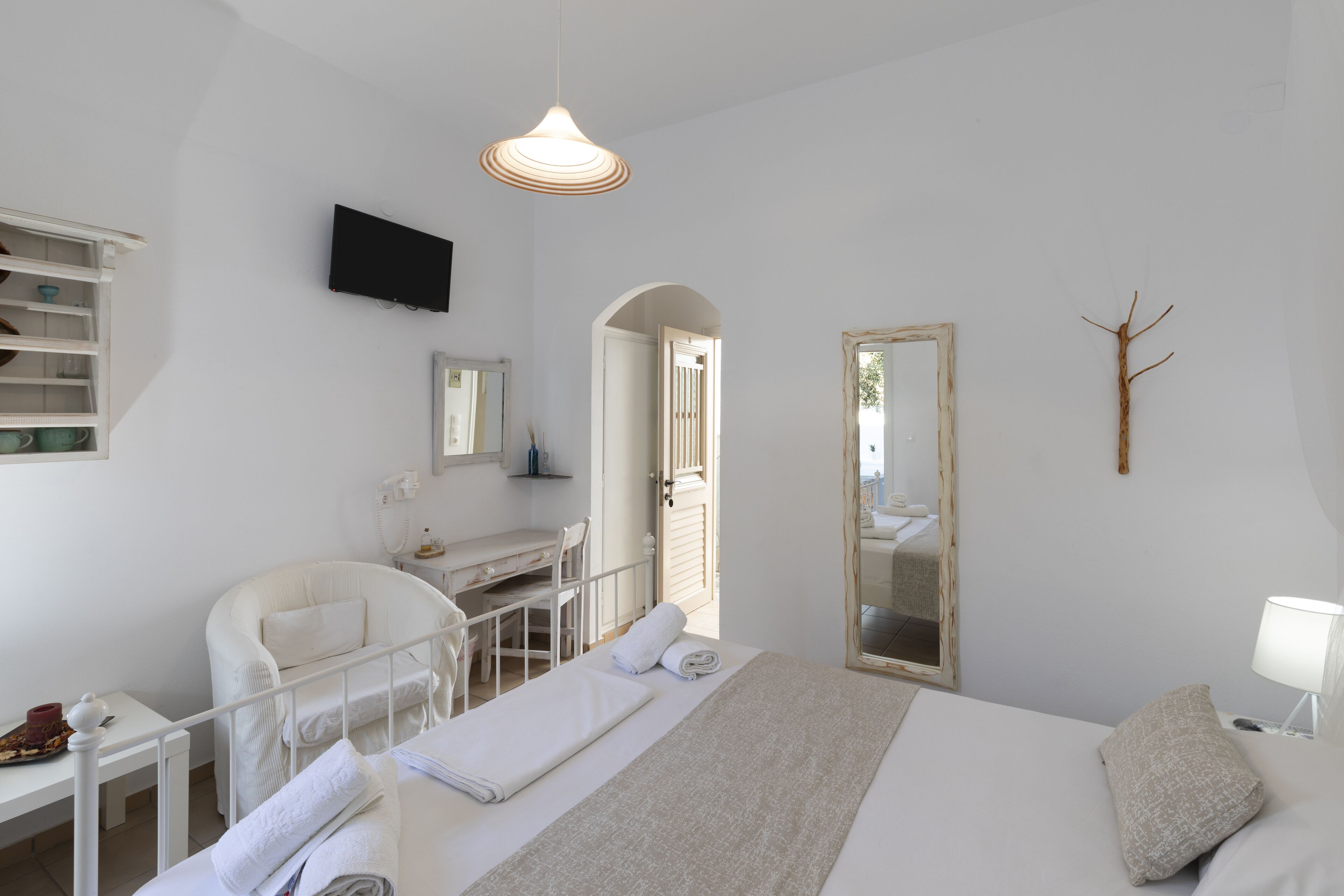 Una camera da letto con un letto, comodino, sedia, scrivania e televisore a parete.