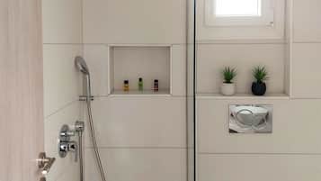 Uma casa de banho moderna com chuveiro, sanita e uma pequena janela sobre a pia.
