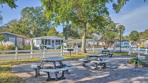 Un parque con mesas de picnic y una cerca blanca.