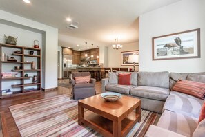 Relax in this stylish living space with a large sofa, coffee table, and bookshelf.