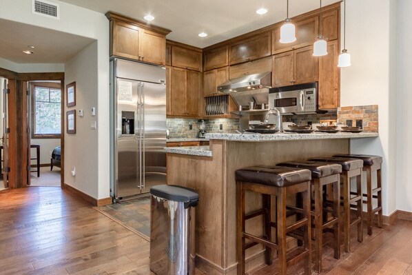 A modern kitchen with wooden cabinets, stainless steel appliances, and a granite countertop. - Woodwinds 25 | Mountain View | Hot Tub (Mammoth Lakes)