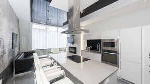 Une cuisine moderne dotée d’un îlot central, d’appareils électroménagers en acier inoxydable et d’un mur d’accent en briques.