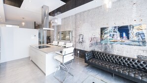 Une cuisine moderne avec un îlot central, des meubles blancs et un canapé en cuir noir.