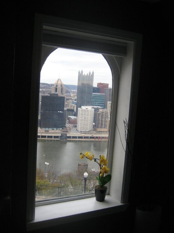 Una ventana con vista a un paisaje urbano, que incluye un edificio distintivo con aguja.