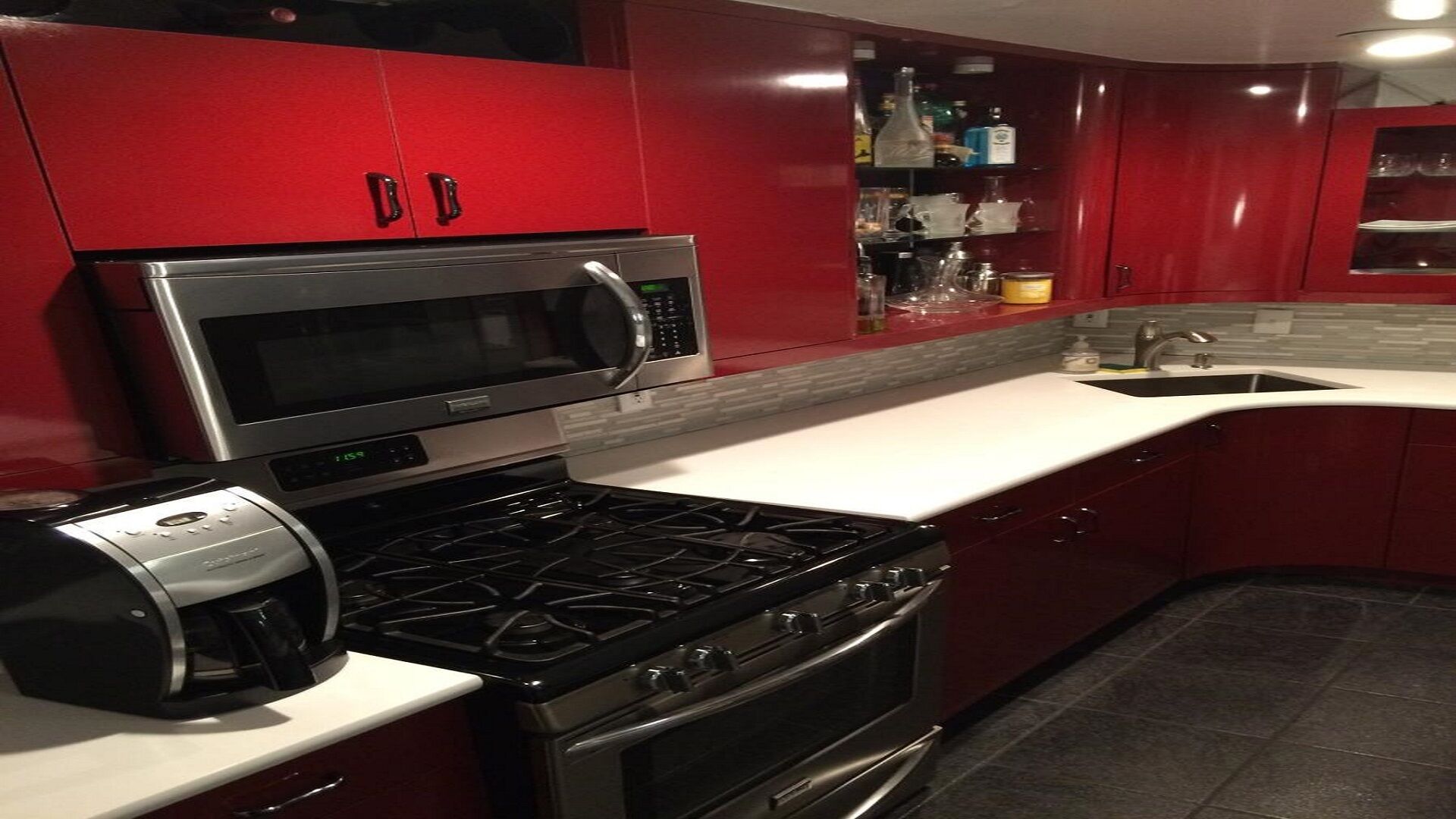 A kitchen with red cabinets, a microwave, a stove, and a coffee maker.