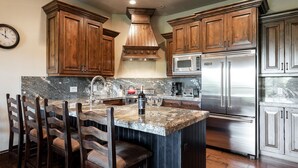 A kitchen with wooden cabinets, a stainless steel refrigerator, a microwave, and a granite countertop. - Canyons Townhome, Views & Gondola Access (Park City)