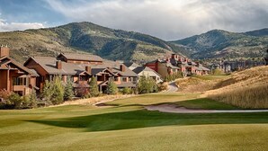 A resort with multiple wooden cabins, a well-maintained golf course, and mountains in the background. - Canyons Townhome, Views & Gondola Access (Park City)