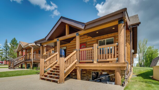 A log cabin-style building with a wooden deck, a staircase, and a covered porch.
