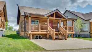 A log cabin-style building with a front porch, a red door, and a staircase leading to the entrance.