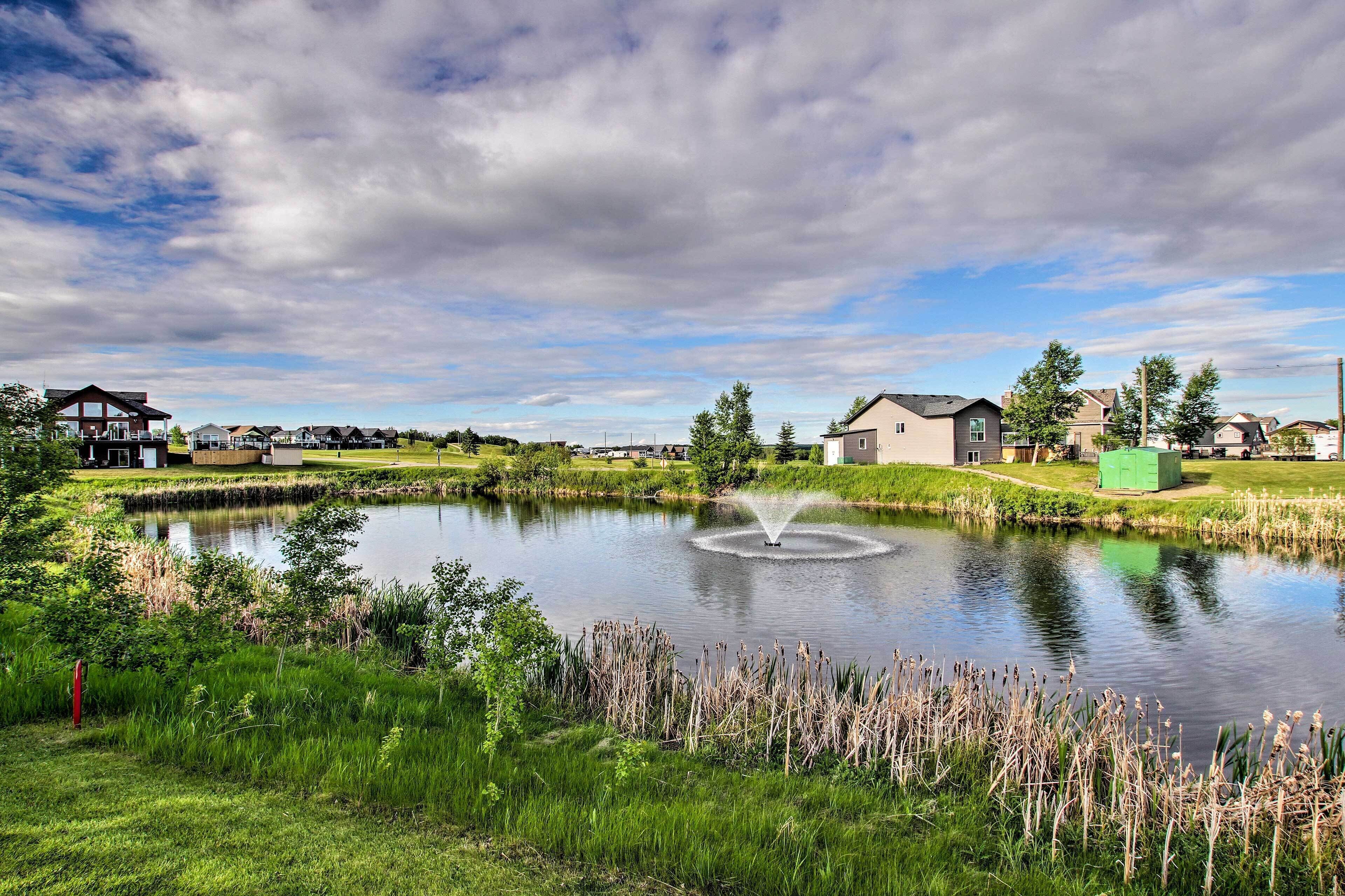 Un quartier résidentiel avec des maisons, un étang et une fontaine.