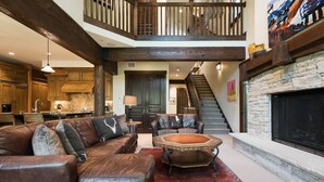 A spacious living area with a brown leather sofa, a round coffee table, and a stone fireplace. - Silver Star 15 | Steps to Lift | Hot Tub (Park City)