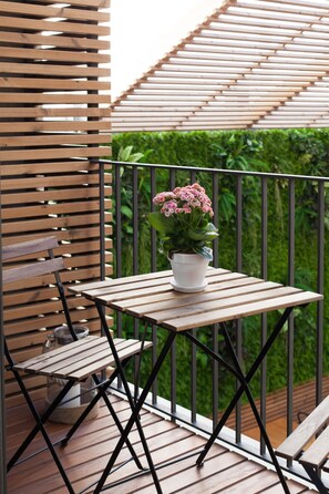 A wooden table with a potted plant on a balcony with a metal railing and a wooden bench. - 7g Roaster Apartments (Vila Nova de Gaia)