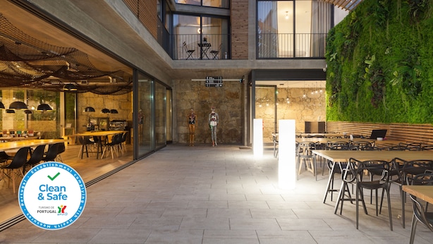 A modern building with a glass facade, outdoor seating area, and a green wall with plants. - 7g Roaster Apartments (Vila Nova de Gaia)