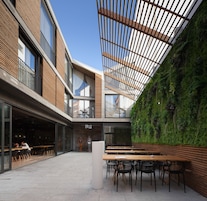 Un edificio moderno con fachada de vidrio, interior de madera y un muro vertical cubierto de jardín.