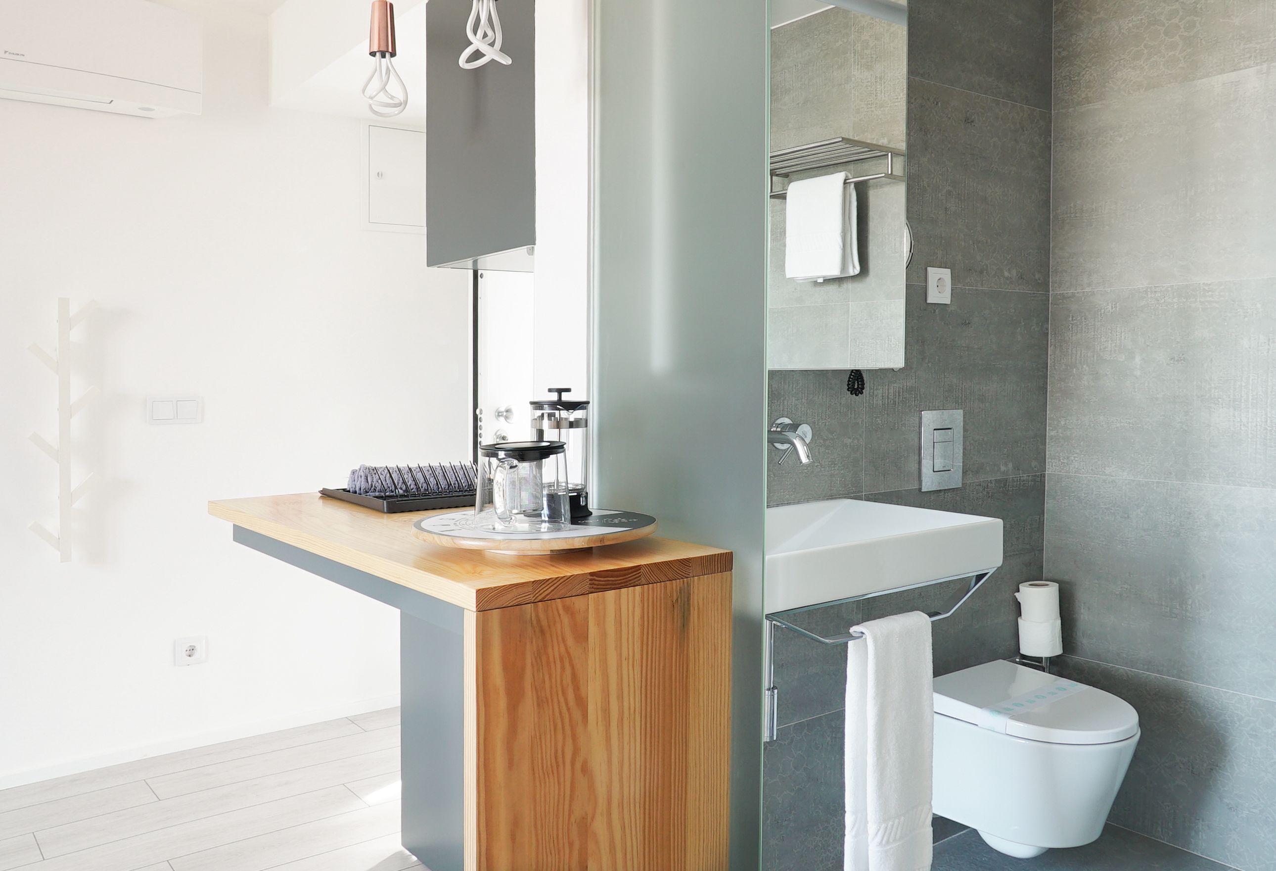 Une salle de bain moderne avec un meuble-lavabo en bois, une cabine de douche en verre et des toilettes blanches.
