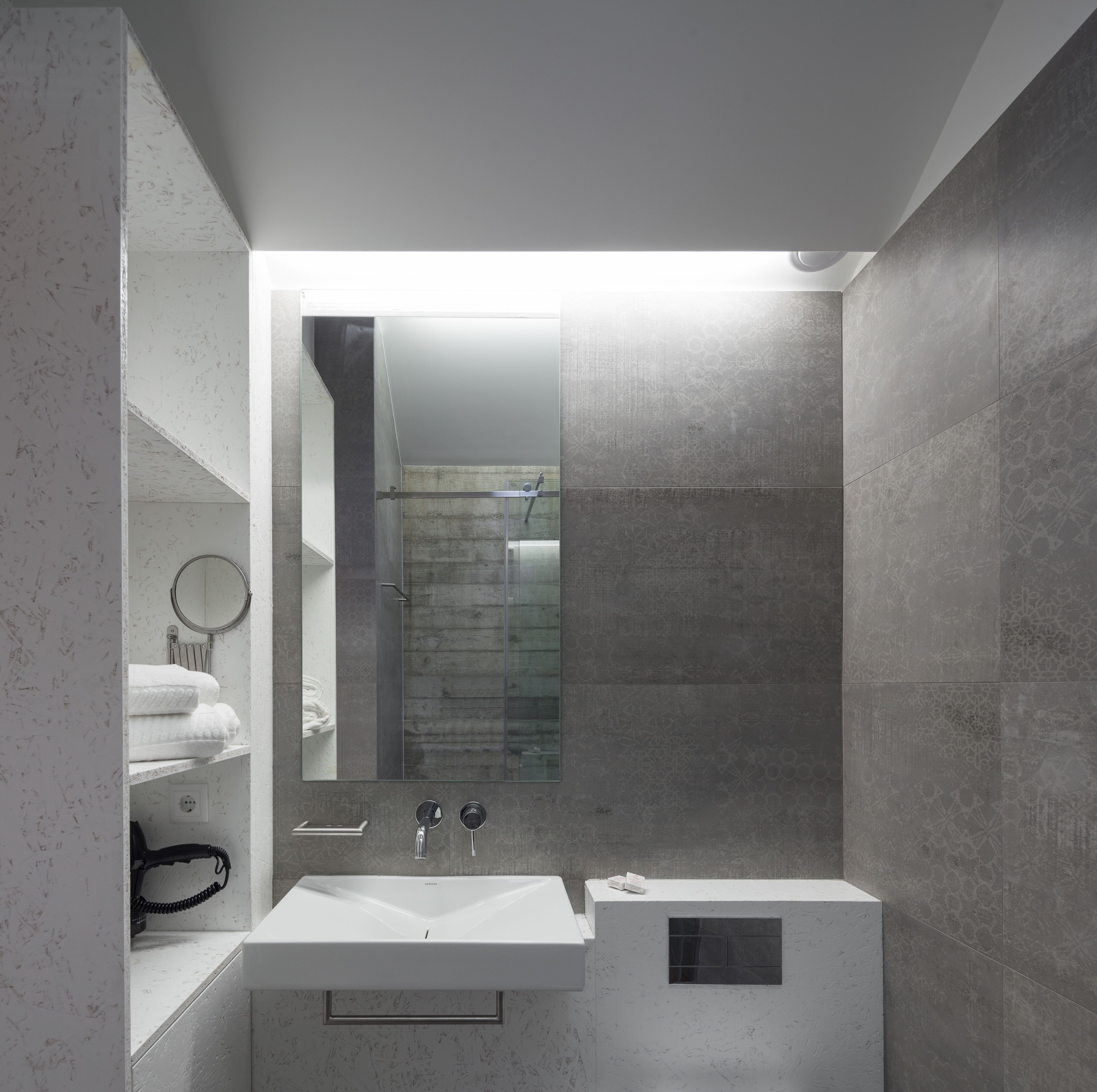 Un baño moderno con un lavabo blanco, un espejo y una cabina de ducha.