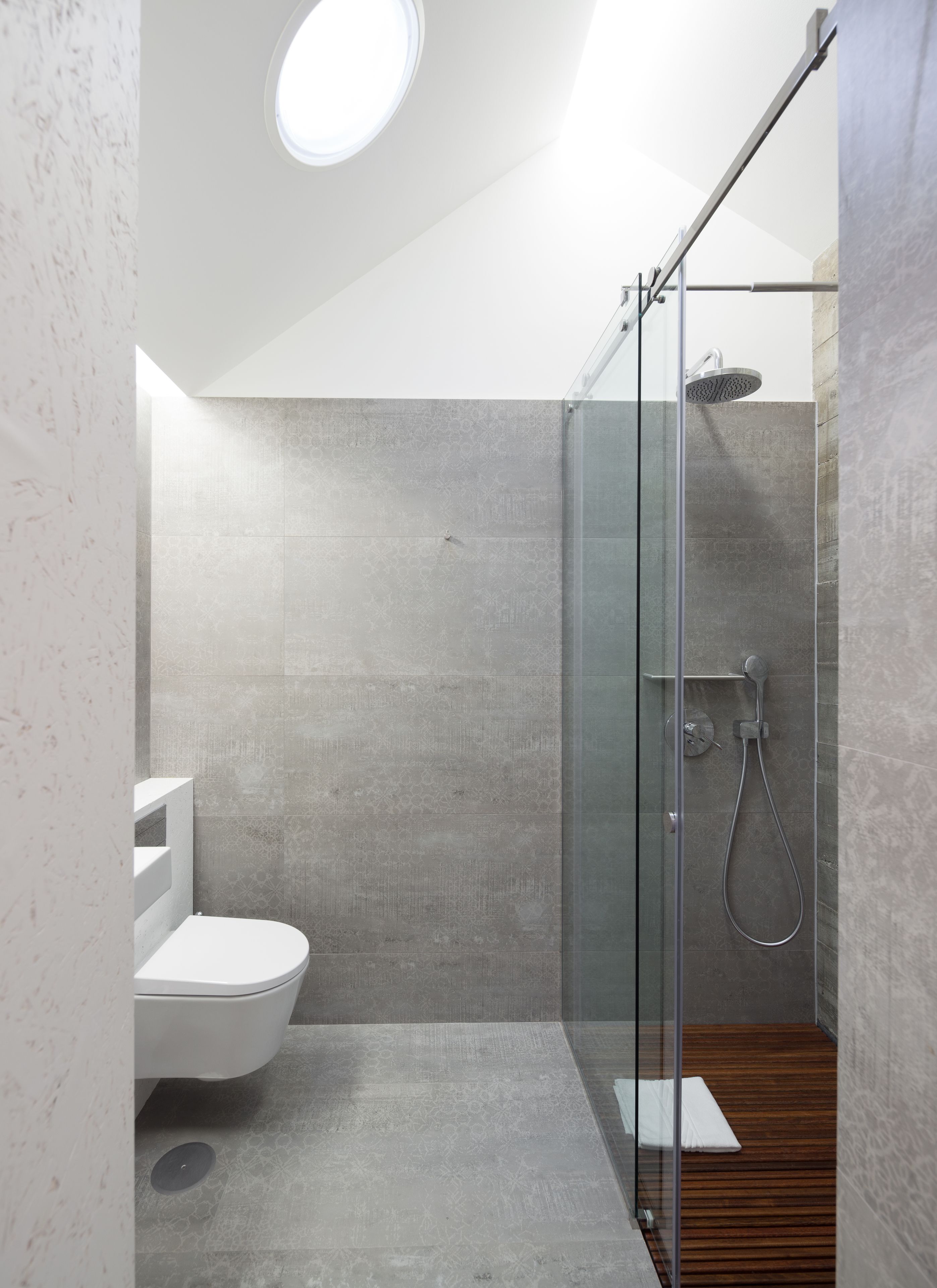 Un baño moderno con ducha de vidrio, inodoro y piso de madera.