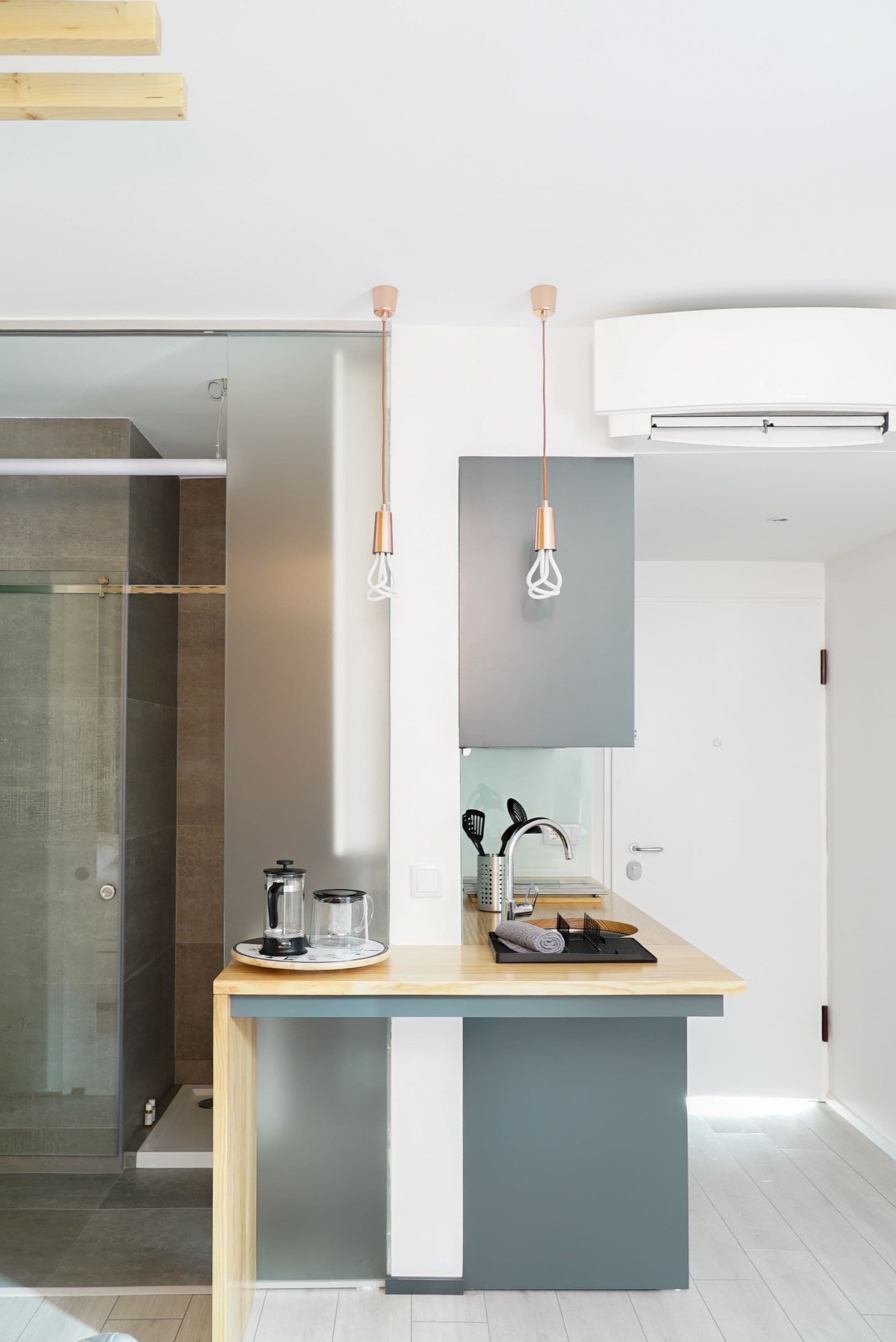 A modern kitchen with a central island, a glass shower enclosure, and pendant lighting.
