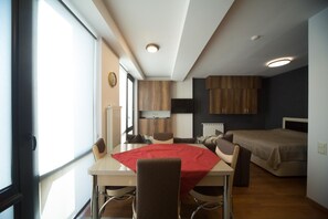 A compact room with a dining table, a bed, and a kitchenette. - LUX apartment (Borjomi)