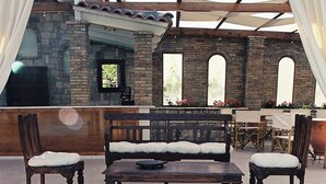 An outdoor seating area with a round table, benches, and chairs. - Nicolas Village Club (Aigialeia)