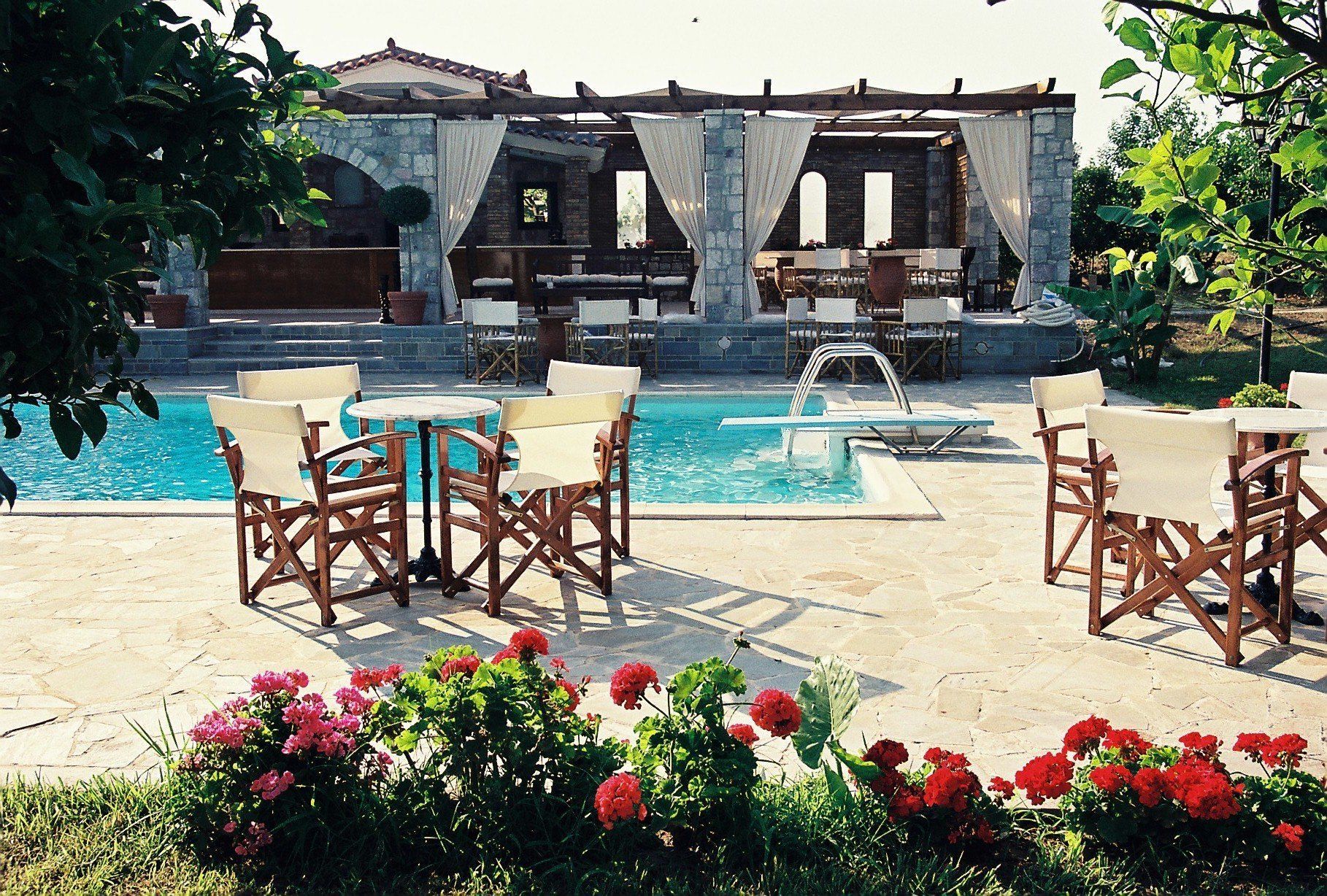 A poolside area with outdoor seating and a stone building in the background.