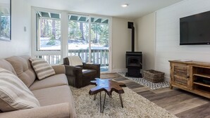 Un salon moderne avec un canapé beige, un fauteuil en cuir marron, une table basse en bois, un téléviseur fixé au mur et une cheminée.