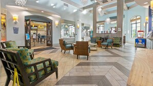 Un vestíbulo amplio con techos altos, candelabros modernos y una variedad de zonas de estar, incluyendo sofás y sillones.