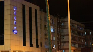 Un hotel con fachada moderna, con ventanas verticales y un llamativo letrero de neón.