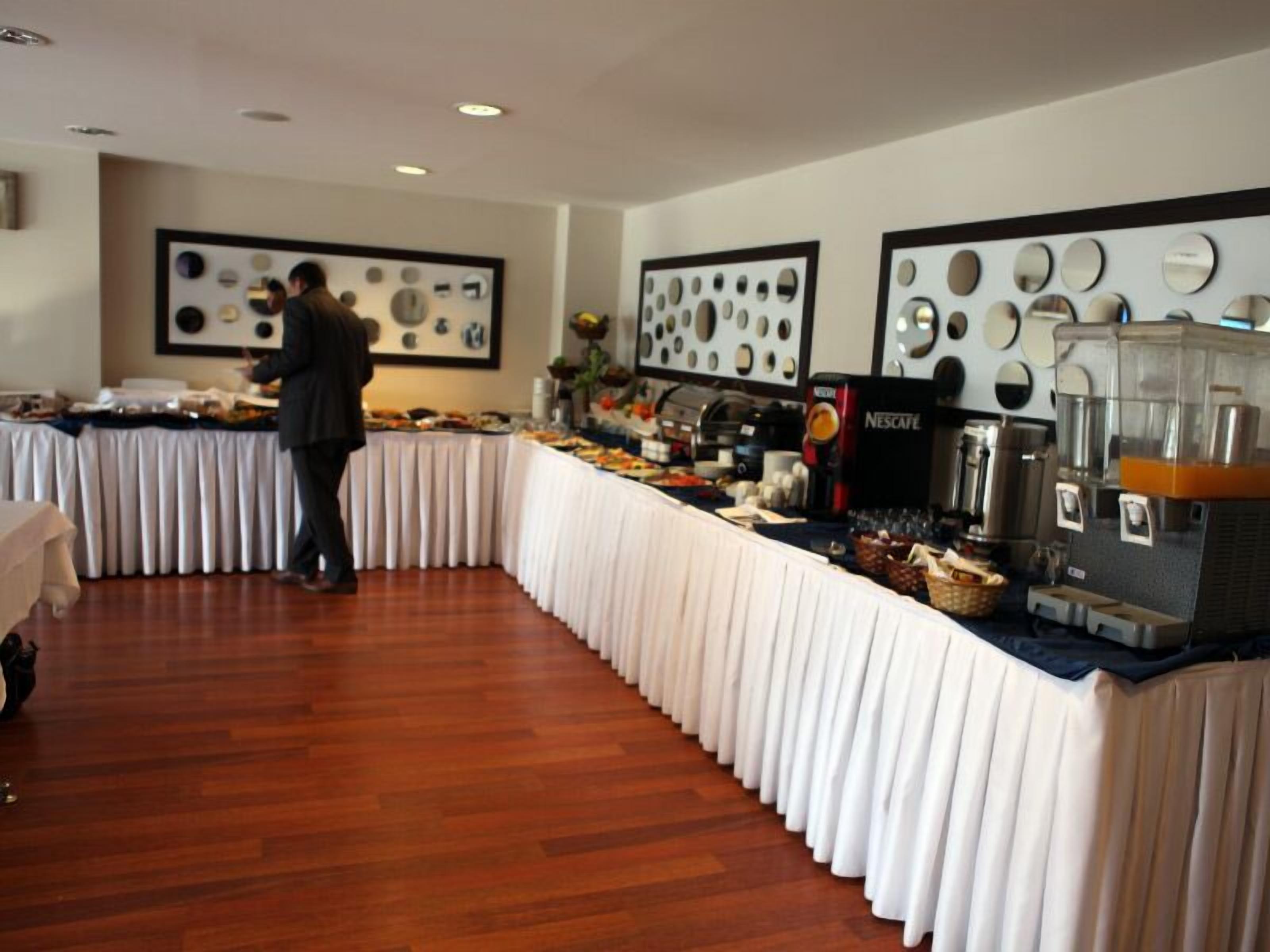 Un buffet proposant une variété de plats, une machine à café et une personne chargée de servir.