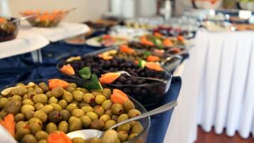 A buffet table with various food items including olives, carrots, and black beans.