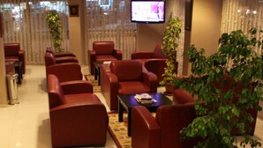 Un hall de hotel con sofás de cuero rojo, una mesa de centro y una pantalla de televisión.