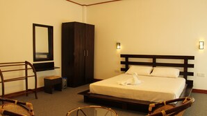 Habitación de hotel con cama, armario, silla y una mesita.