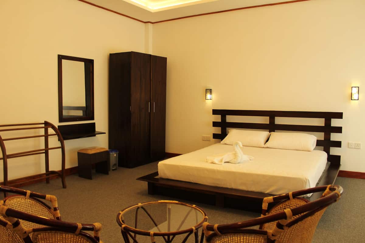 A hotel room with a bed, a wardrobe, a chair, and a small table.