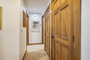A hallway with wooden doors and a framed picture on the wall.
