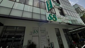 Un hotel moderno con fachada de vidrio, señalización de 'S&B Boutique Hotel' y una entrada visible.