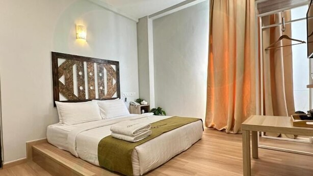 Una habitación de hotel moderna con una cama, una mesita y vistas al exterior.