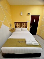 Una habitación de hotel con una cama, una mesita de noche, un teléfono en la pared, una puerta y un equipo de aire acondicionado de pared.